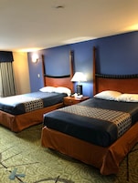 Habitación de hotel con dos camas, una mesita de noche, una lámpara y una ventana con cortinas.