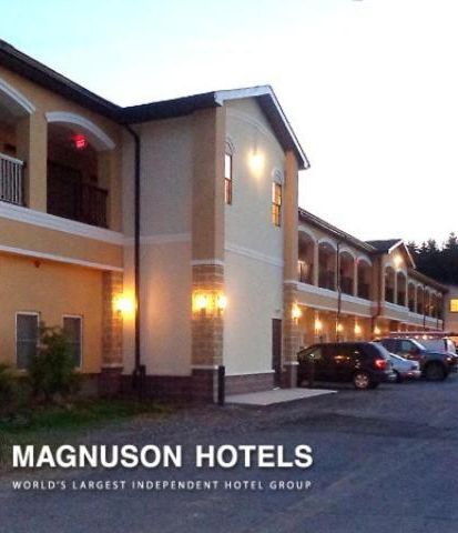 A hotel with a row of rooms, a covered outdoor area, and a parking lot.