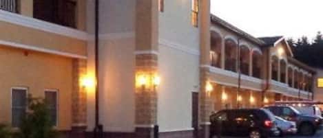 A hotel with a row of rooms, a covered outdoor area, and a parking lot.