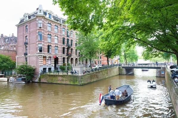 A canal with boats, a bridge, and a building with balconies. - Hotel Amsterdam Inn - Digital Access (Amsterdam)