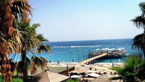 A beachside resort with wooden structures, a pier extending into the sea, and a clear view of the ocean. - Mukarnas Spa & Resort (Alanya)