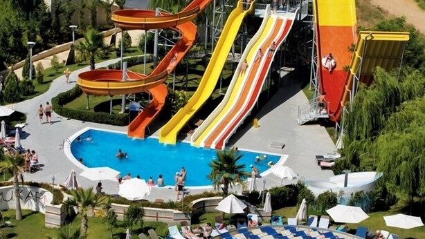A resort with a large pool, multiple water slides, and a beach area. - Mukarnas Spa & Resort (Alanya)