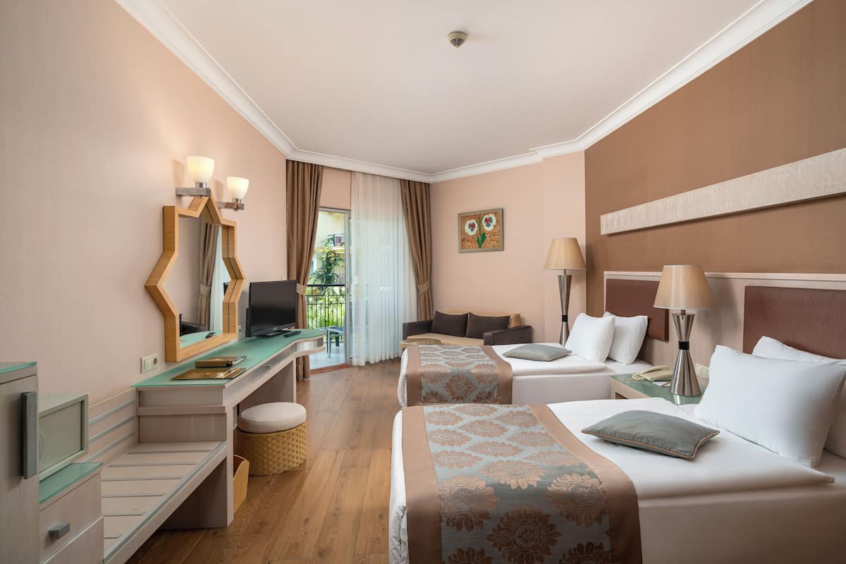 Habitación de hotel con escritorio, dos camas, una silla y vistas al exterior.