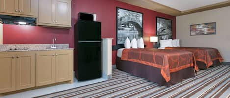 Habitación de hotel con kitchenette, una cama con dos sábanas, un ventanal grande y piso alfombrado.