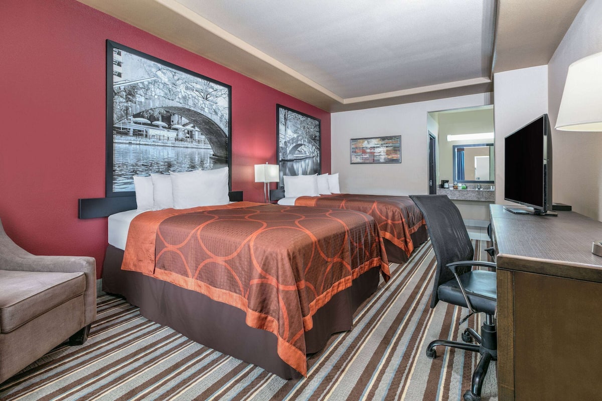 A hotel room with a large bed, a desk, a chair, and a television.