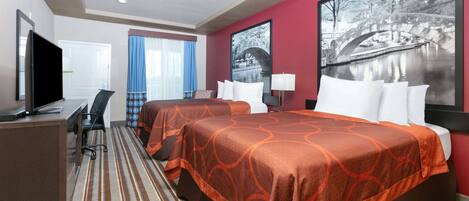 Habitación de hotel con dos camas, un escritorio, un televisor y un ventanal con cortinas.