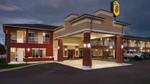A motel with a red exterior, multiple balconies, and a Super 8 sign.