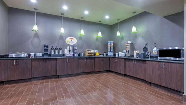 A commercial kitchen with stainless steel appliances, a coffee station, and a sign for a breakfast menu.