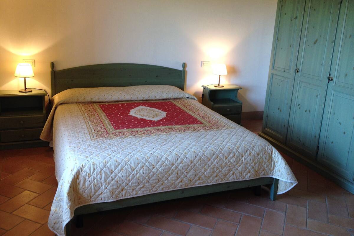 Ein Schlafzimmer mit einem Bett, zwei Nachttischen, einem Schrank und einem Kleiderschrank.