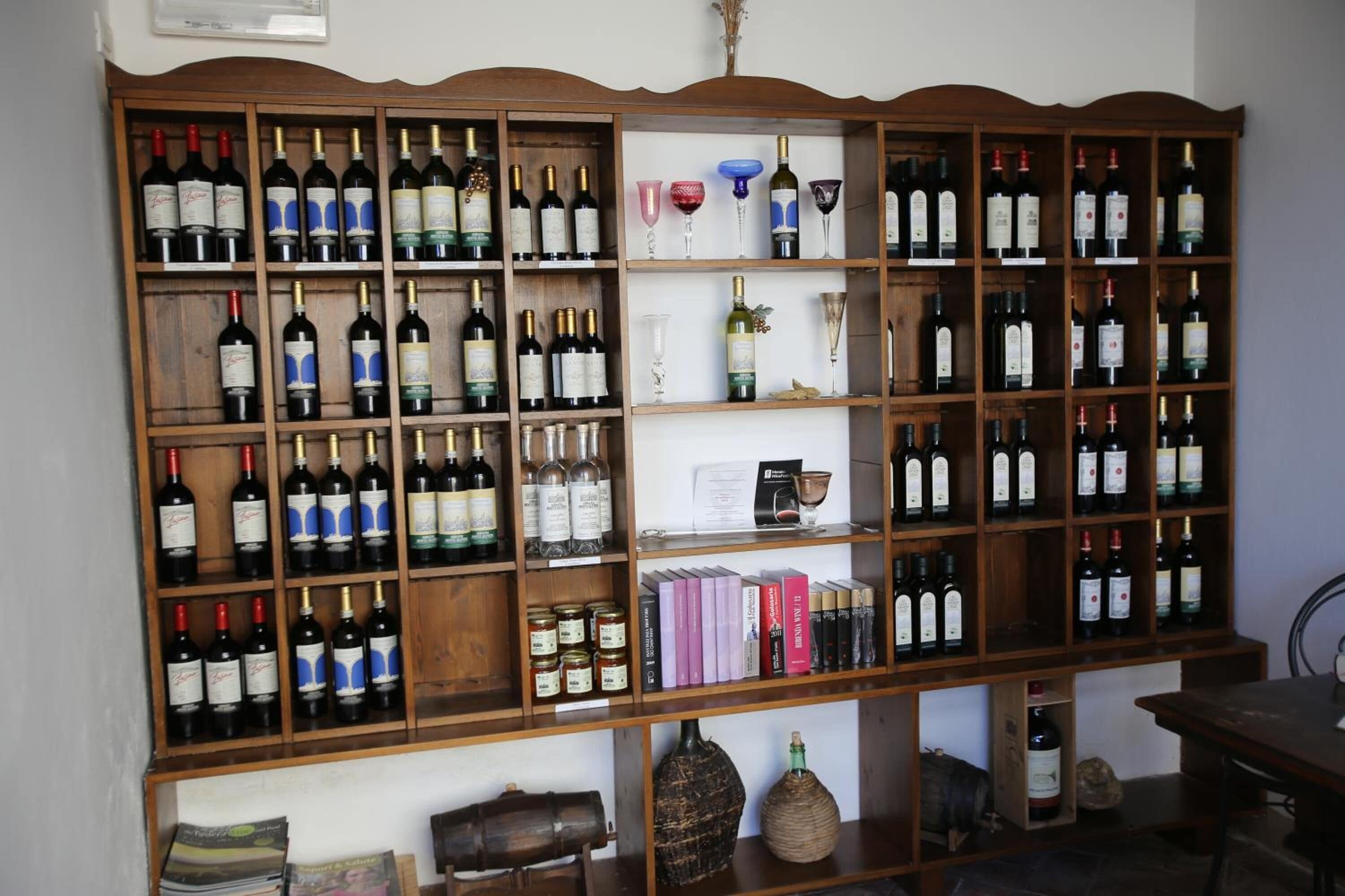 Una botellera de madera con varios estantes que sostienen botellas de vino y copas.