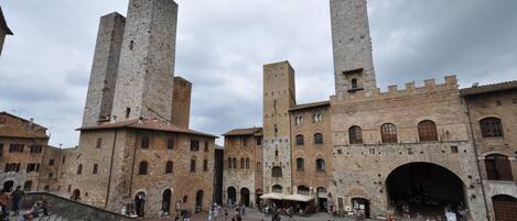 A historic square with medieval buildings, including tall towers and arched doorways.