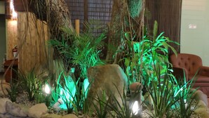 A tropical indoor garden with a stone border, large rocks, and green plants. - Dao Diamond Hotel (Tagbilaran)