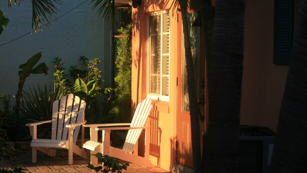 A house with a porch, a white chair, and a small garden.