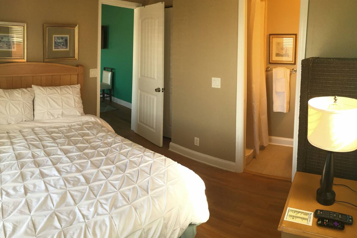 Une chambre d’hôtel avec un grand lit, une lampe et une télécommande posée sur une table.