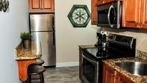 A kitchen with wooden cabinets, stainless steel appliances, a granite countertop, and a potted plant.