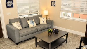 A living room with a grey sofa, a dark coffee table, and a lamp.