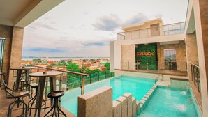 A rooftop pool with a view of the city, a bar area, and a sign reading 'Splazh!' - Hotel XYZ (Tacloban)