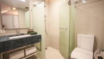 Un baño moderno con ducha de vidrio, lavamanos de mármol y un inodoro con dispensador de toallas de papel.