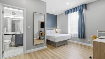 A modern hotel room with a bed, bedside table, and a desk.