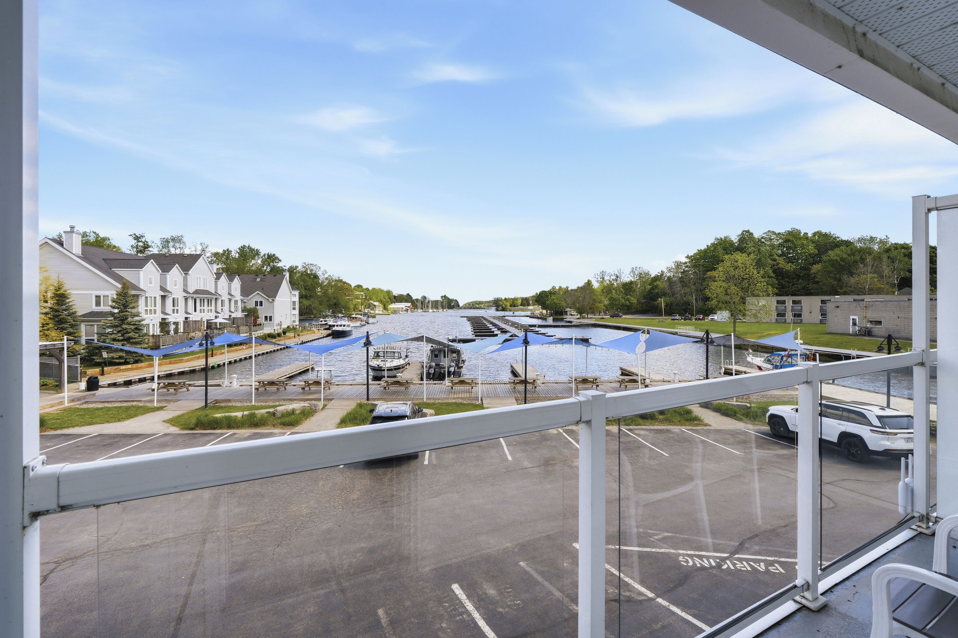 A view from a window overlooking a marina with boats, a parking lot, and residential buildings in the background.