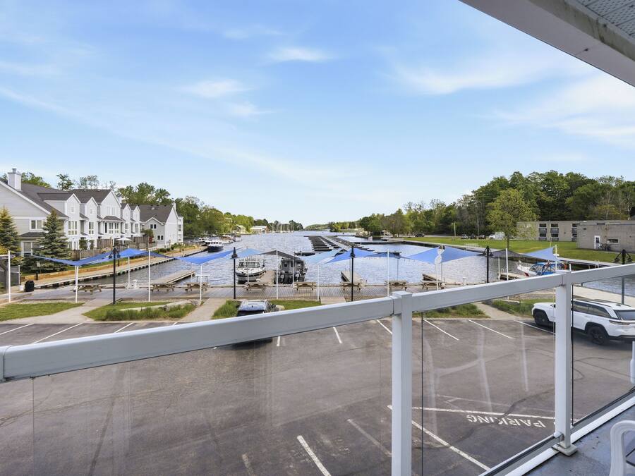 A view from a window overlooking a marina with boats, a parking lot, and residential buildings in the background.