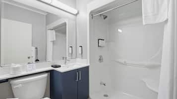 Un baño moderno con inodoro, lavabo, espejo y cabina de ducha.