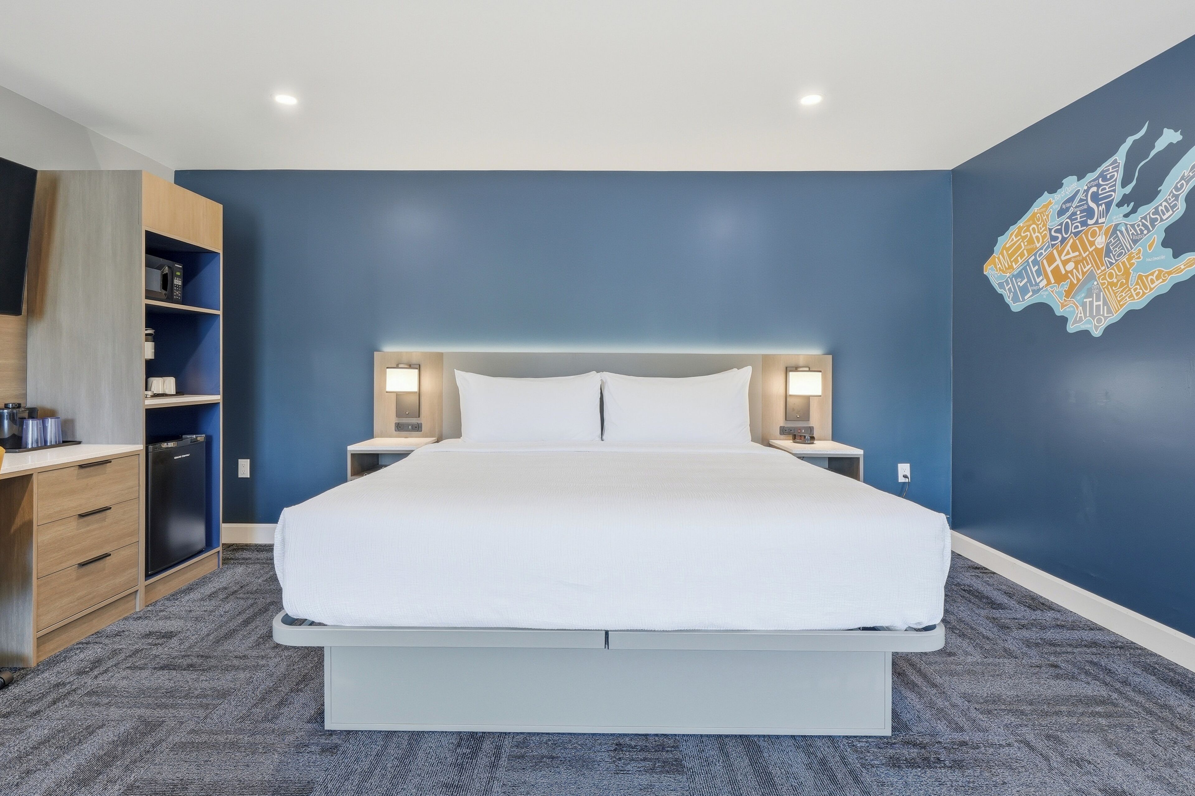 Una habitación de hotel moderna con una cama grande, lámparas de noche, un escritorio con silla y un armario.