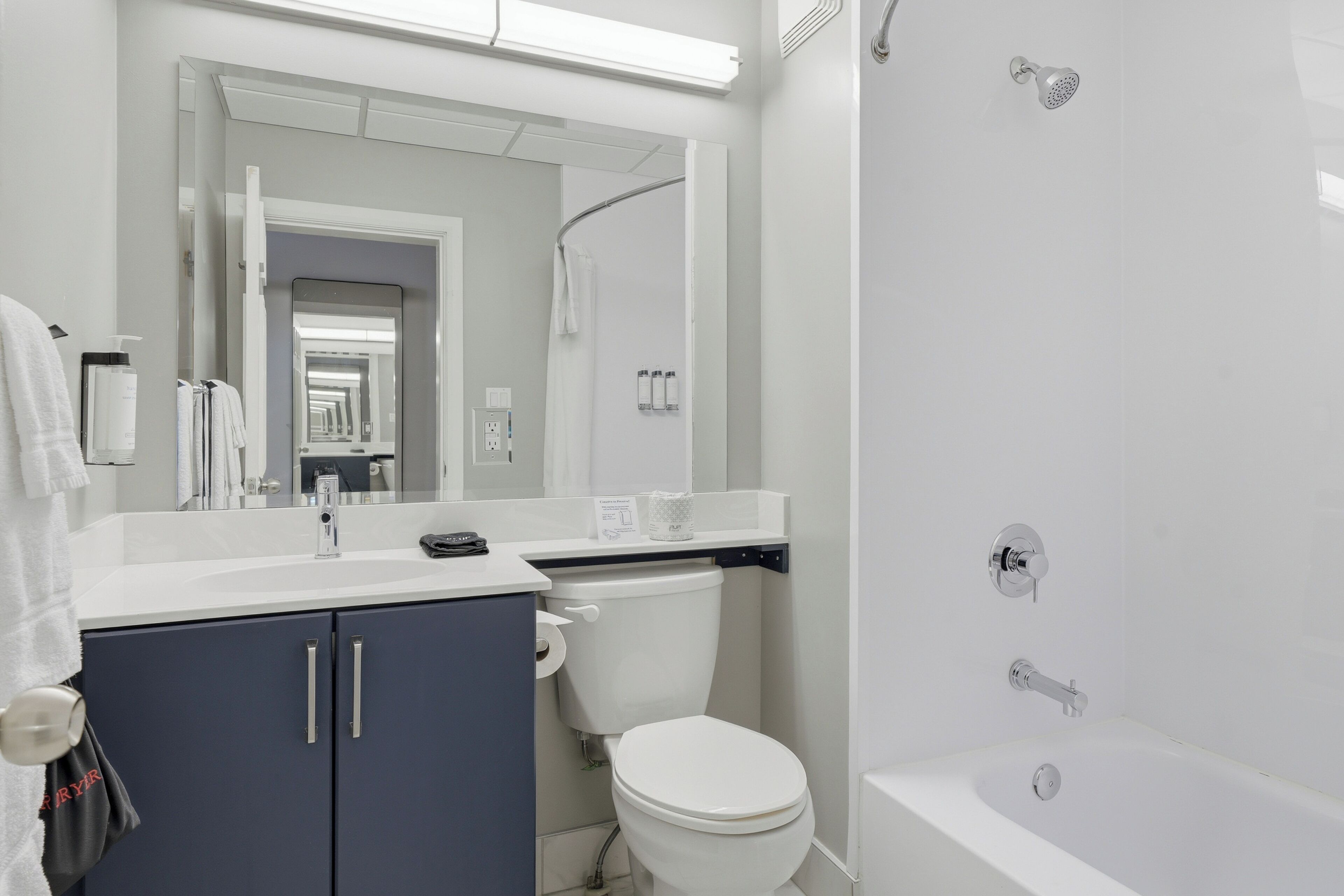 A modern bathroom with a white sink, vanity, toilet, and bathtub.