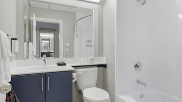 A modern bathroom with a white sink, vanity, toilet, and bathtub.