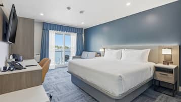 Une chambre d’hôtel équipée d’un lit, d’un bureau, d’une chaise, d’une table de chevet et d’un téléviseur fixé au mur.