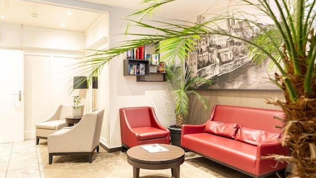 A modern hotel lobby with a red sofa, two armchairs, a coffee table, and a bookshelf. - Hotel Alexander (Basel)