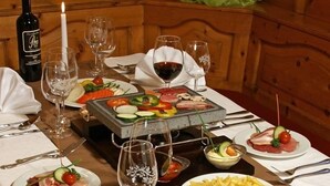 A dining table set with various dishes, including a charcuterie board, a bottle of wine, and a candle. - Hotel Alexander (Basel)