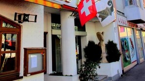 A hotel building with a prominent 'HOTEL' sign and a Swiss flag. - Hotel Alexander (Basel)