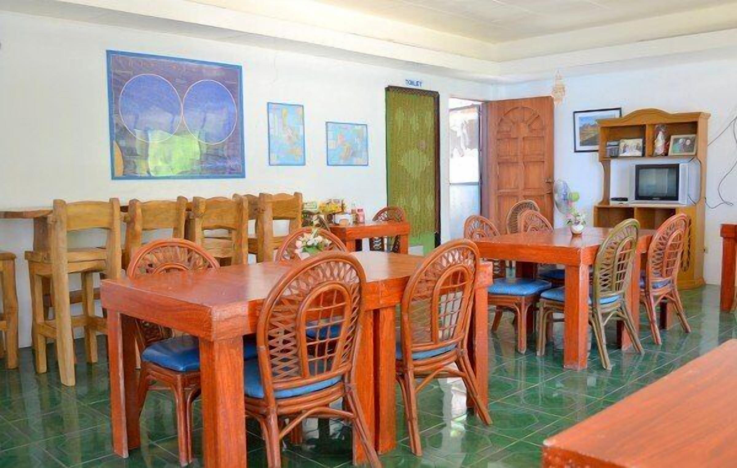 A dining area with wooden tables and chairs, a television, and artwork on the walls.
