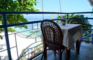 A table with a chair on a balcony overlooking a beach. - Blue Corals Beach Resort (Daanbantayan)