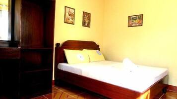 A bedroom with a wooden bed, a wardrobe, and three framed pictures on the wall.