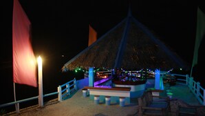 A beachside bar with a thatched roof, wooden seating, and a railing. - Blue Corals Beach Resort (Daanbantayan)