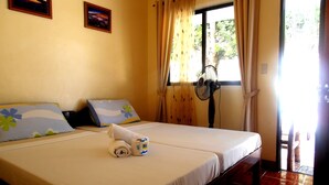 A double bed with a white bedspread, two pillows, a rolled towel, and a fan. - Blue Corals Beach Resort (Daanbantayan)