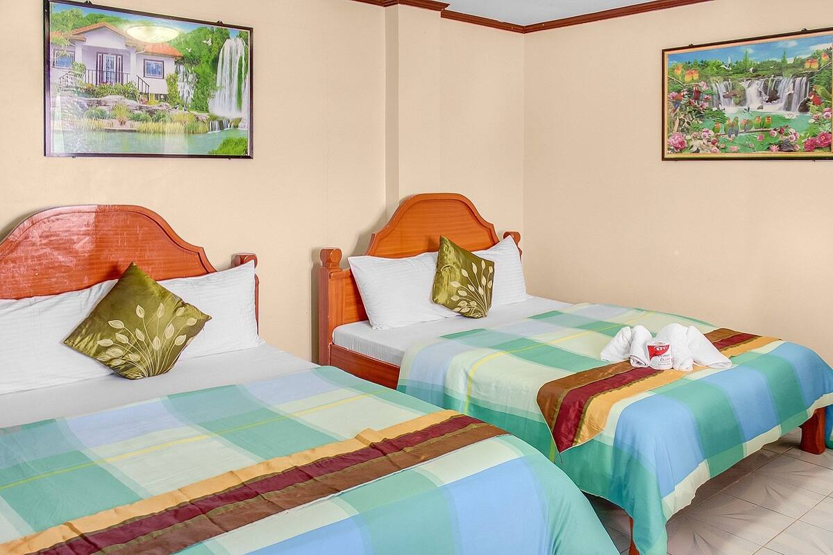 Dos camas con ropa de cama colorida, cabeceros de madera y almohadones decorativos.