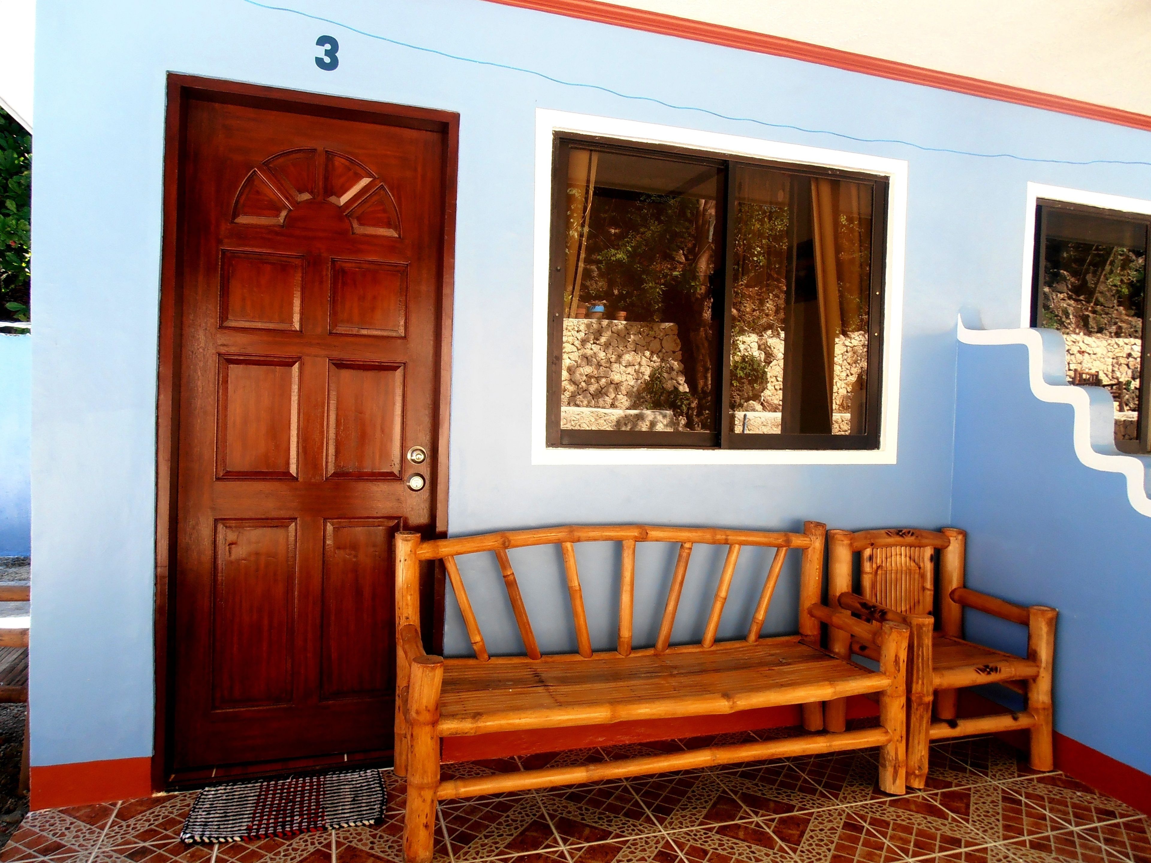A wooden bench outside a building with a blue wall and a number '3' above a door.