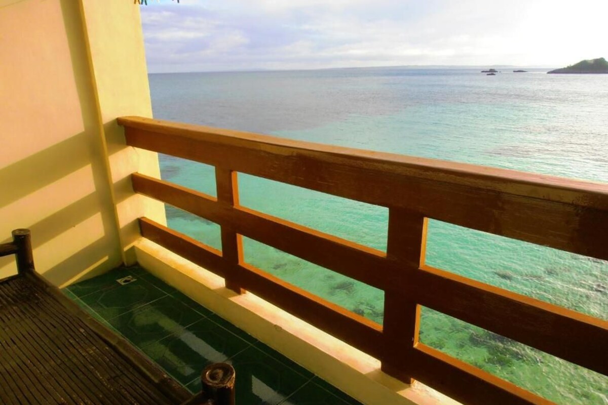 Varanda com grade de madeira e vista para águas azul-turquesa.