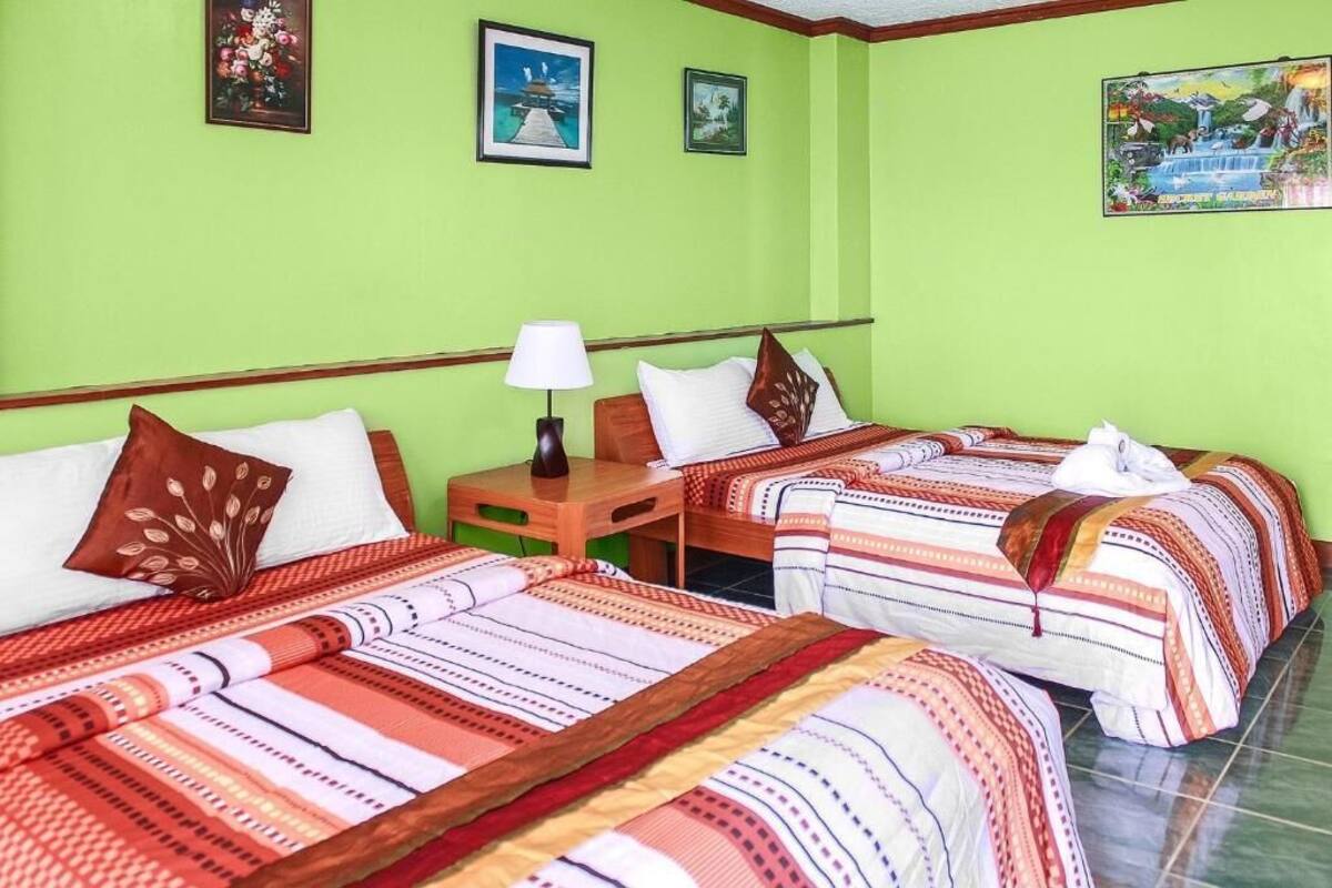 Habitación de hotel con dos camas, una mesita de noche y una lámpara.