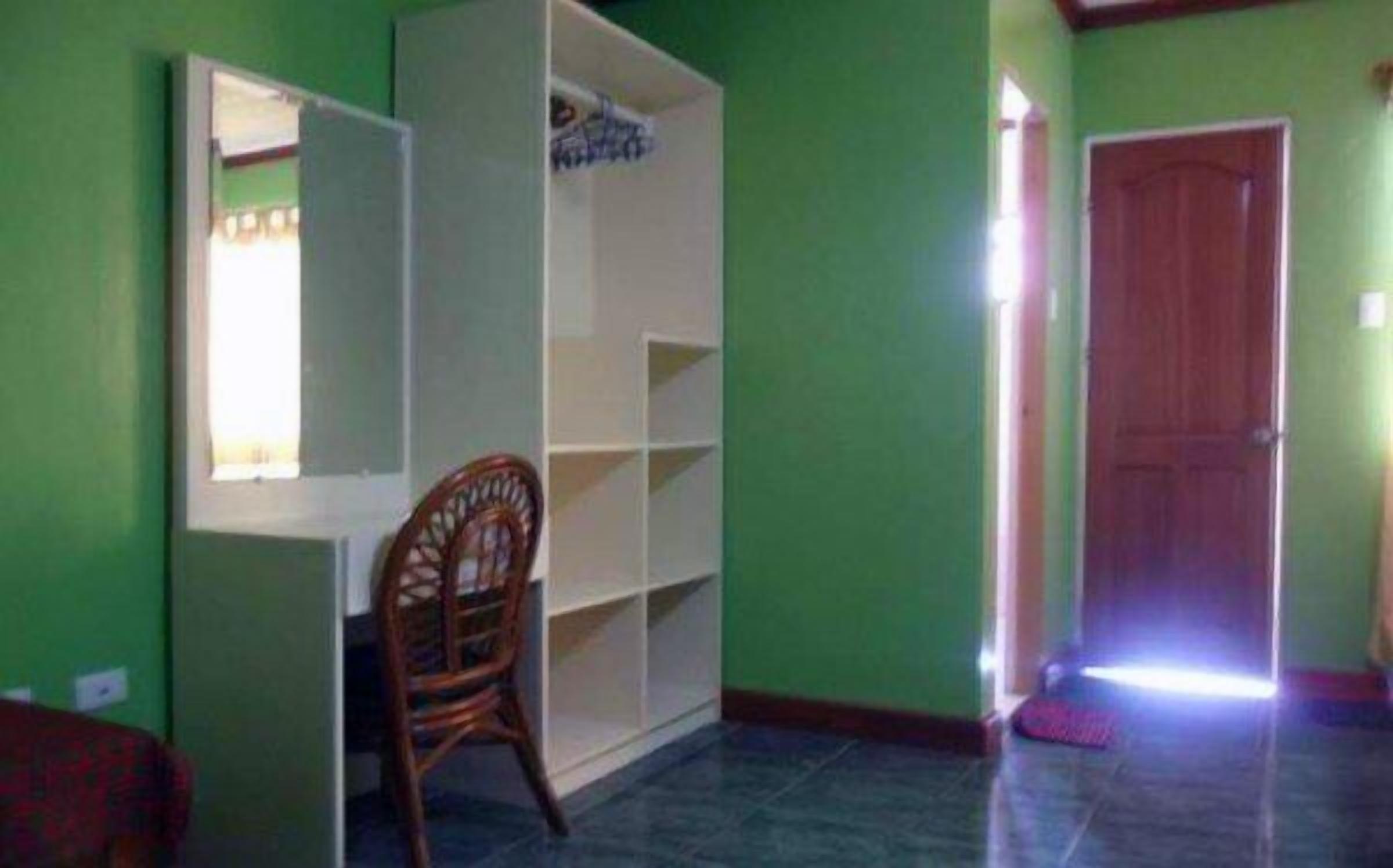 A room with a wooden chair, a white shelving unit, and a closed door.