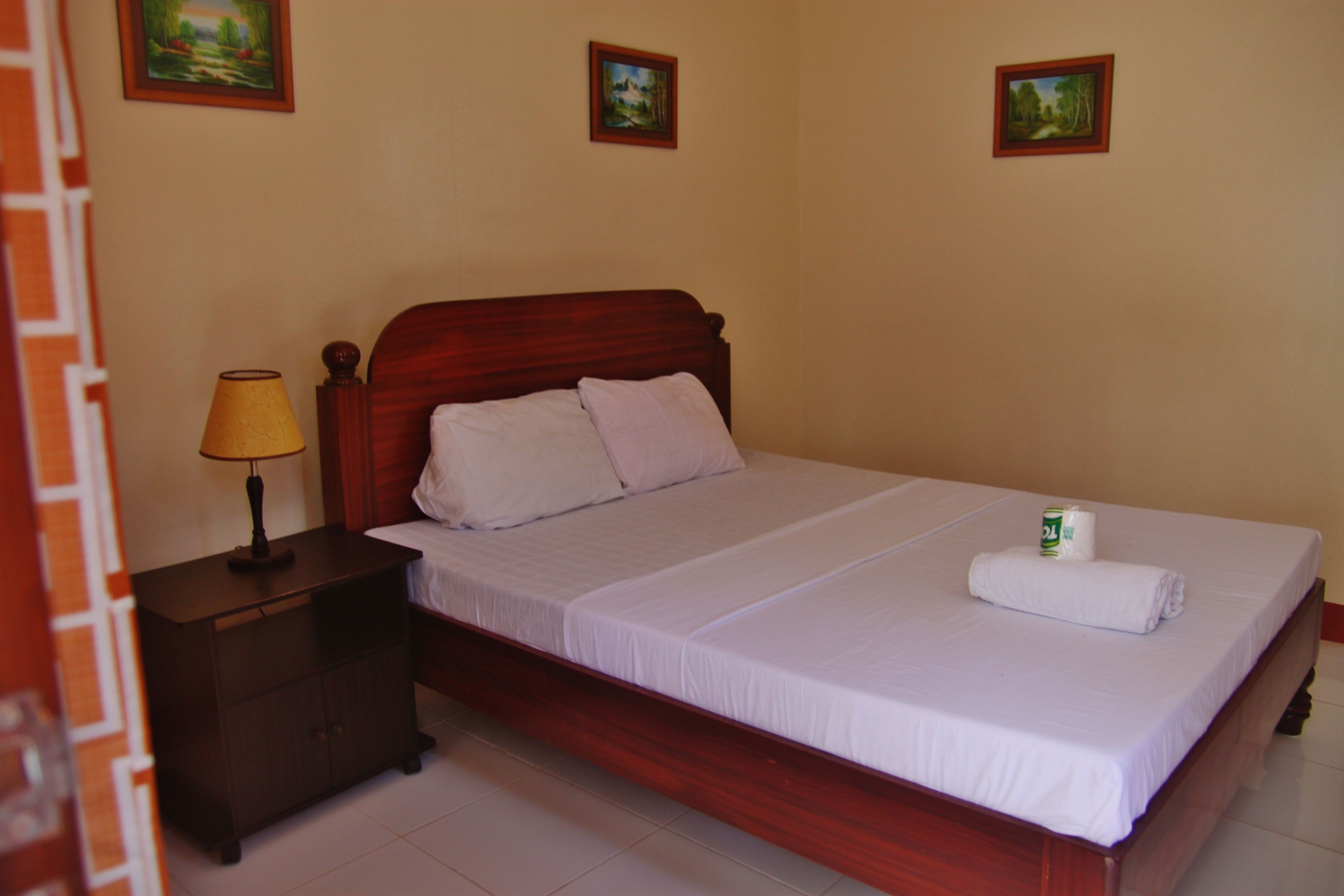A neatly made bed with white linens, a wooden headboard, and a small bedside table with a lamp.