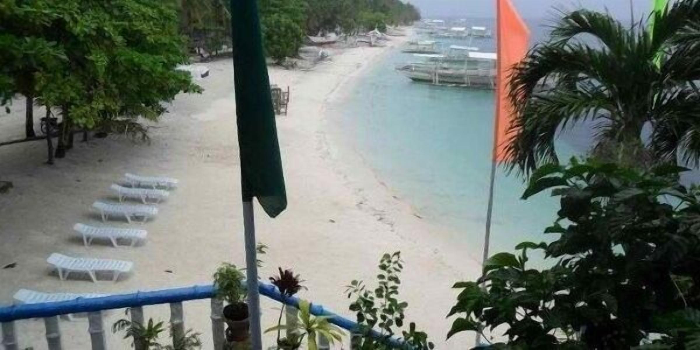 Una playa con sillas reclinables blancas y una bandera.