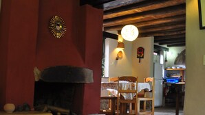 A cozy room with a fireplace, wooden furniture, and a table with a placemat. - Kuychi Rumi (Urubamba)