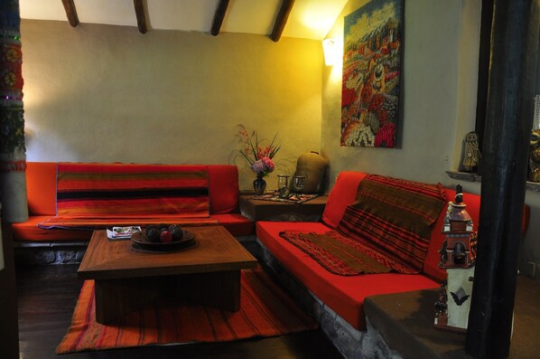 A cozy living room with a red sofa, a wooden coffee table, and a decorative lantern. - Kuychi Rumi (Urubamba)
