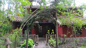 A traditional building with a tiled roof, a wooden gate, and a pathway leading to the entrance. - Kuychi Rumi (Urubamba)