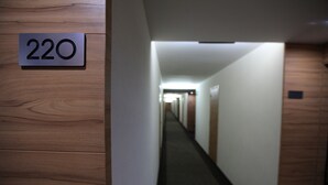 A hallway with a sign indicating room number 220. The hallway has wooden paneling on the walls and a carpeted floor.