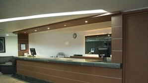 A reception desk with a computer, a clock, and a counter.